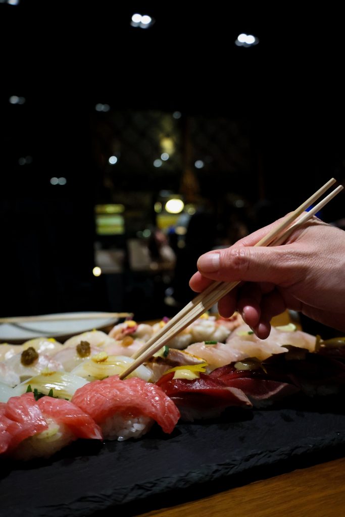 Chopsticks lifting sushi at a candlelit table