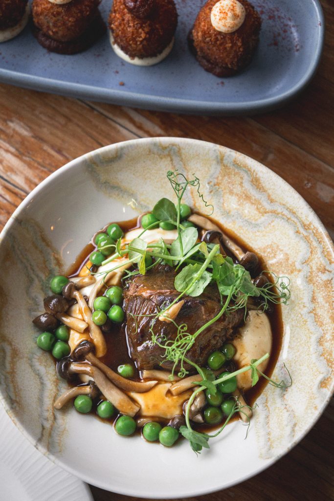 Braised meat with peas, mushrooms and fresh shoots in a marbled bowl