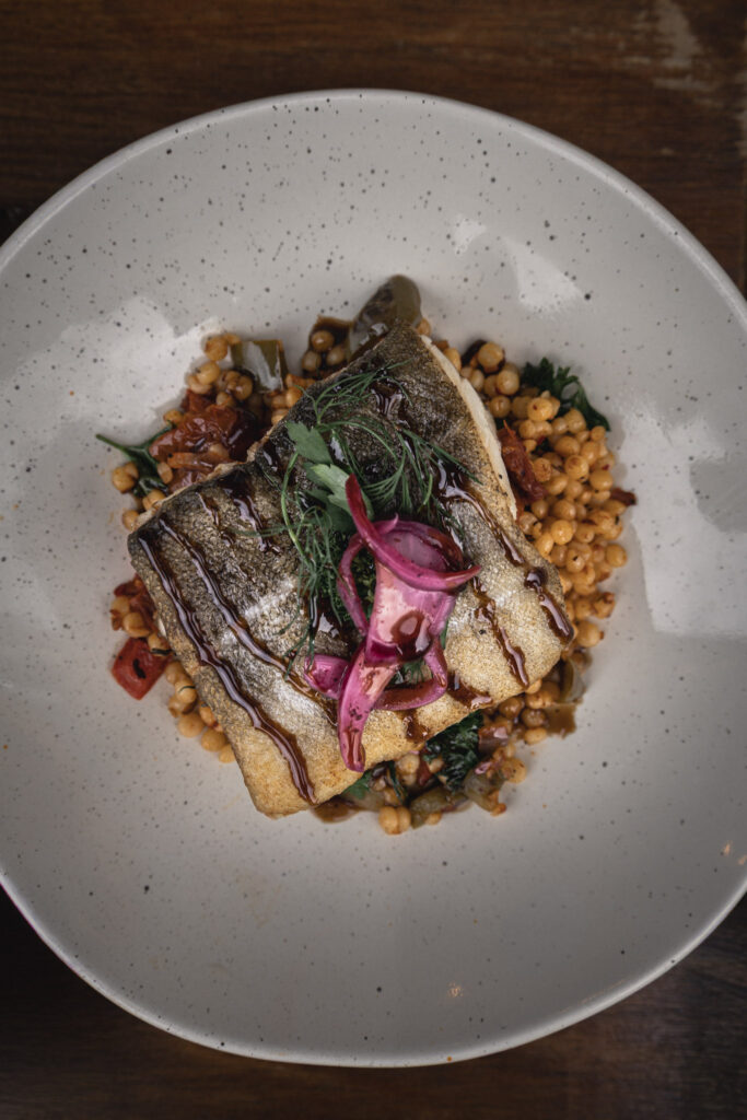 Grilled fish fillet with rice and herbs on a white plate