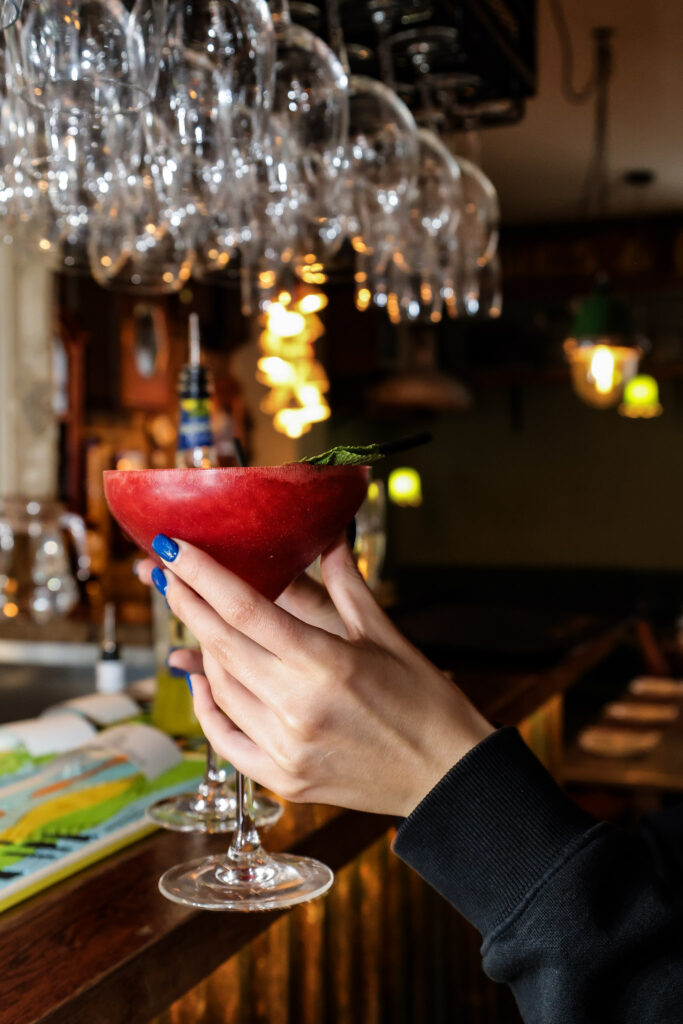 Guest raising a red cocktail at a candlelit bar