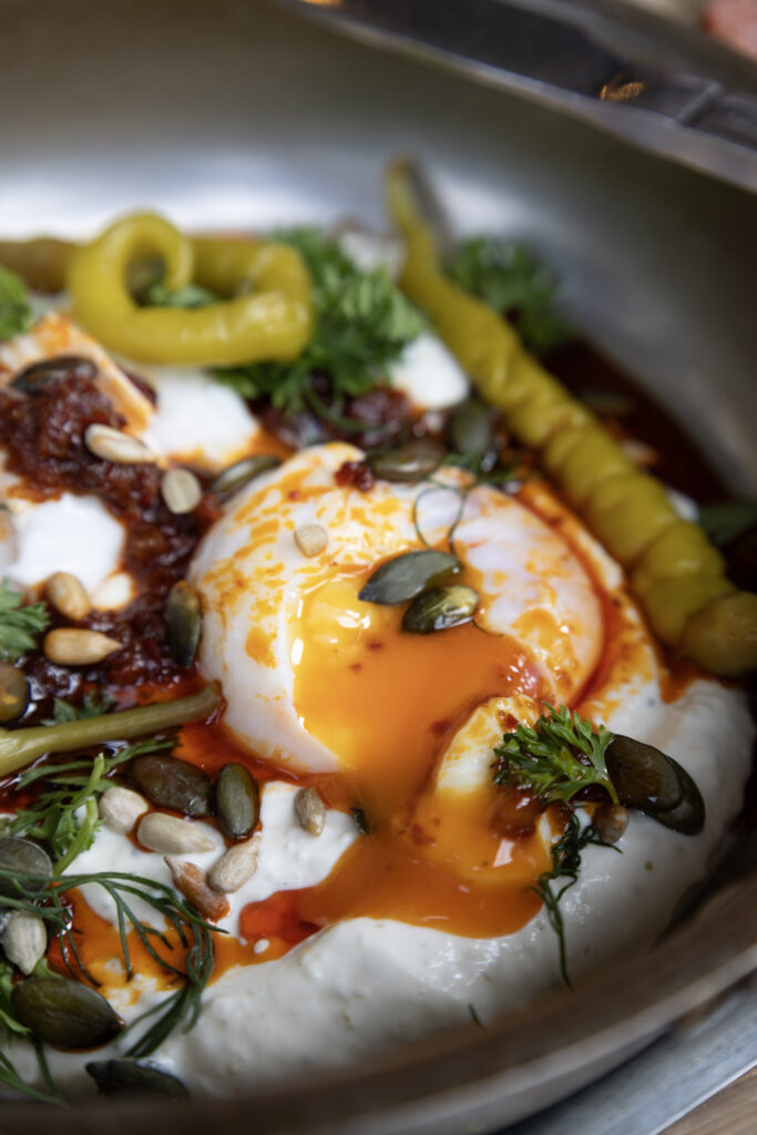 Plated eggs with herbs, peppers and a rich sauce, shot from above